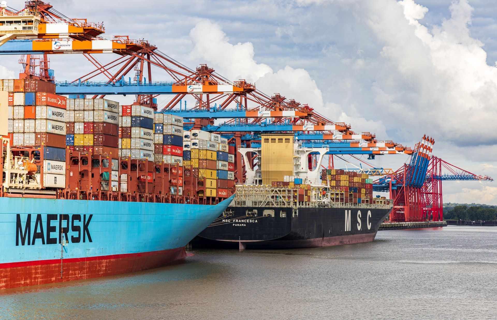 Container ships moored beside harbour cranes, stacked with shipping containers